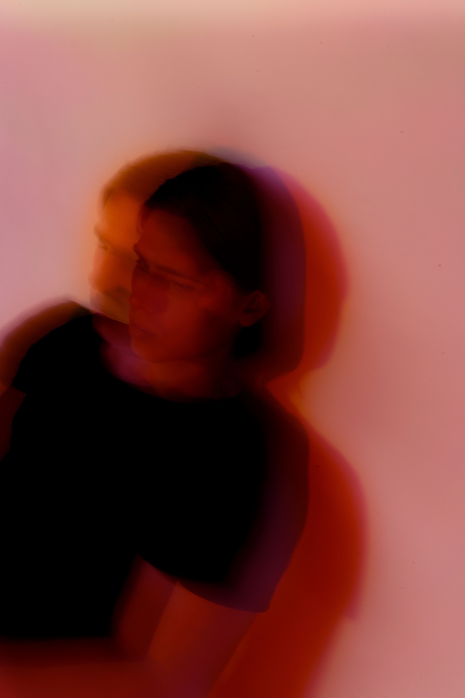 A soft-focus portrait of a woman against a pink wash