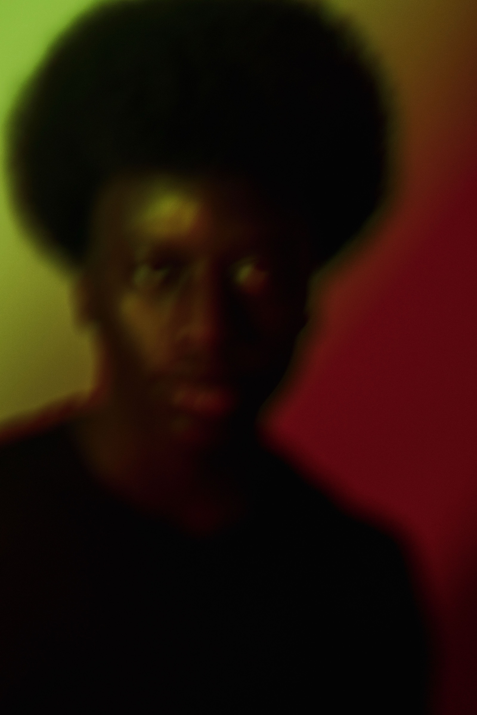 A soft-focus portrait of a young man, lit green on one side and red on the other