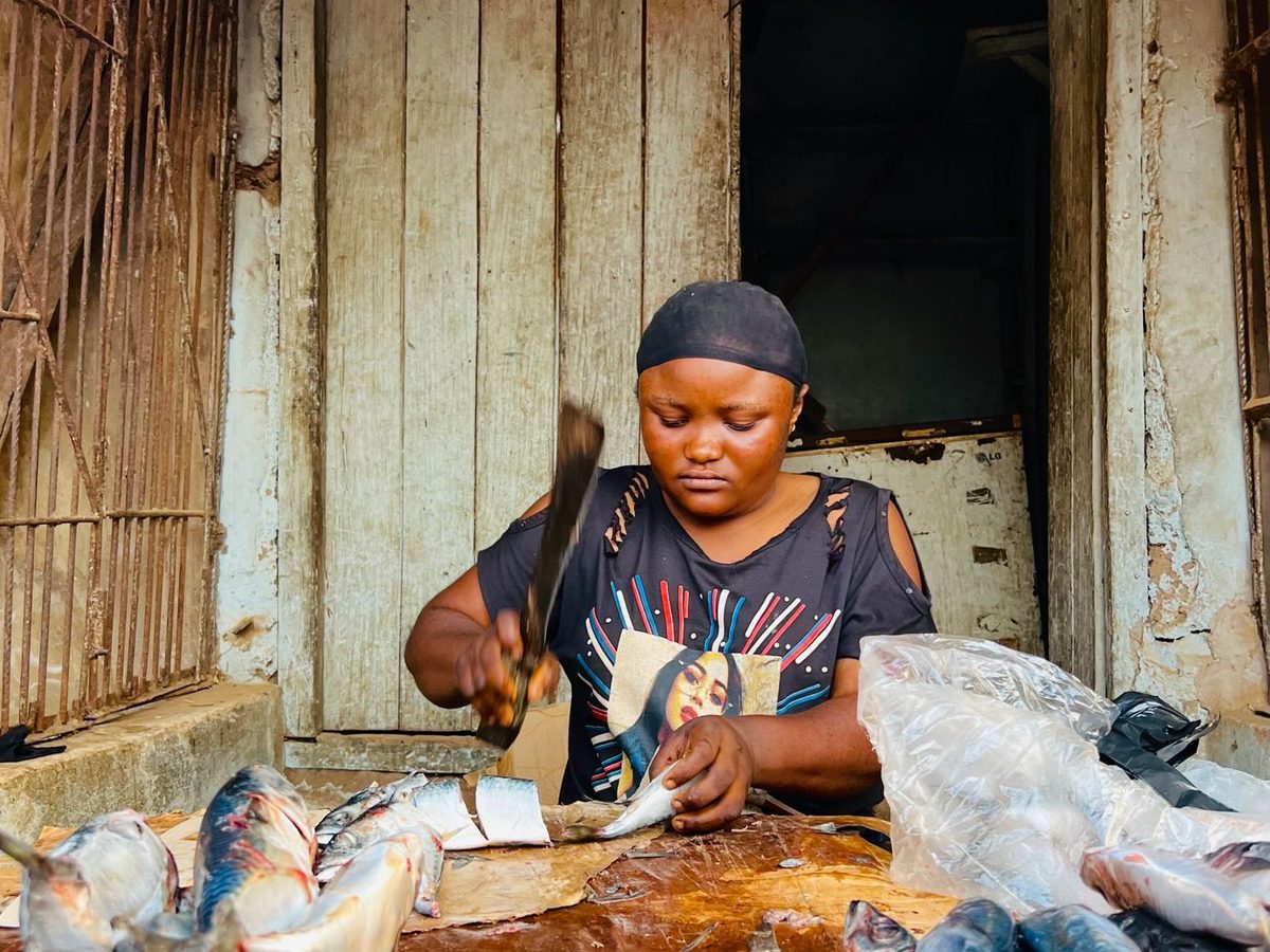 A woman preparing fresh fish at a market stall